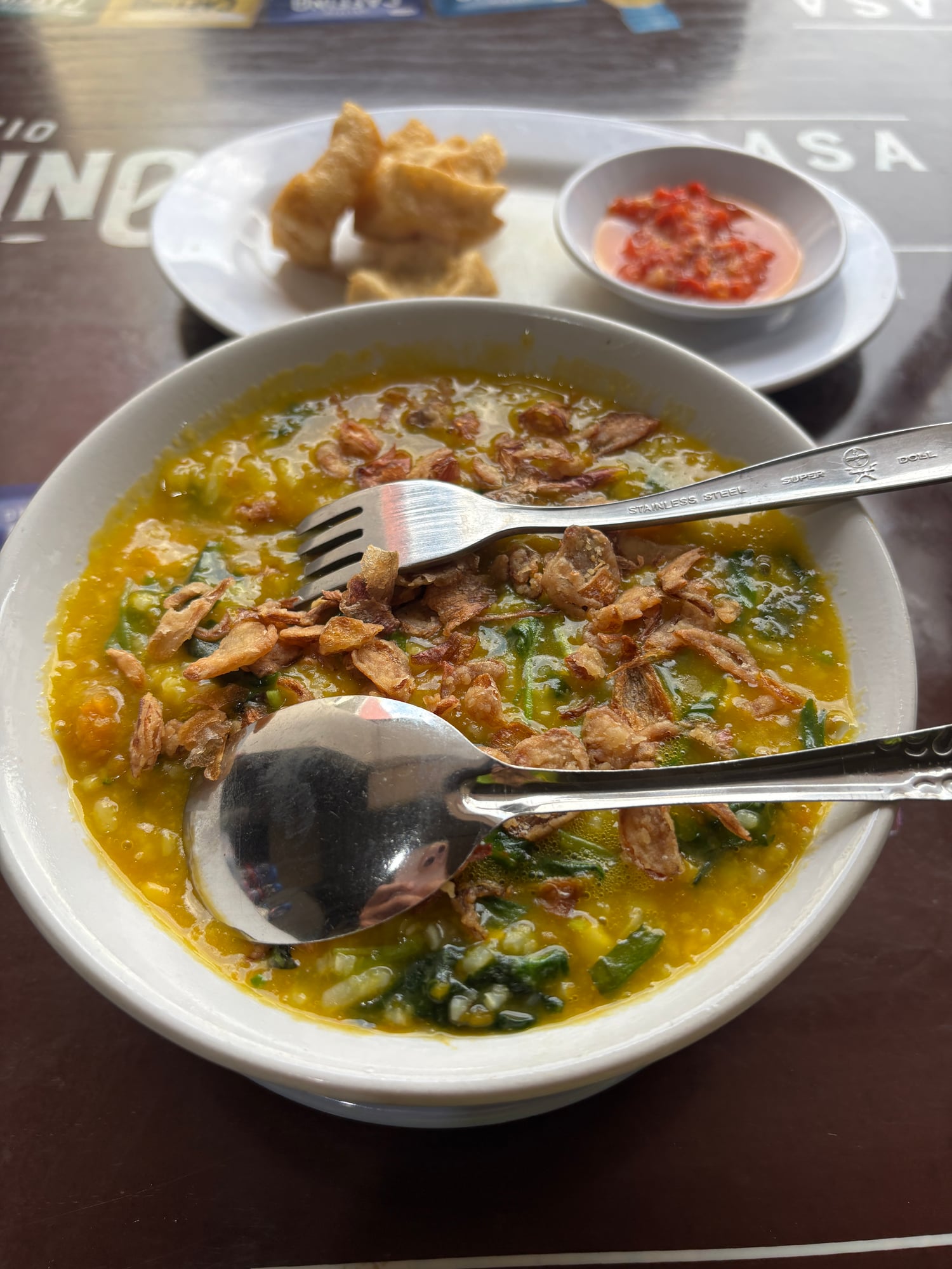 A bowl of Bubur Manado porridge topped with crispy fried shallots