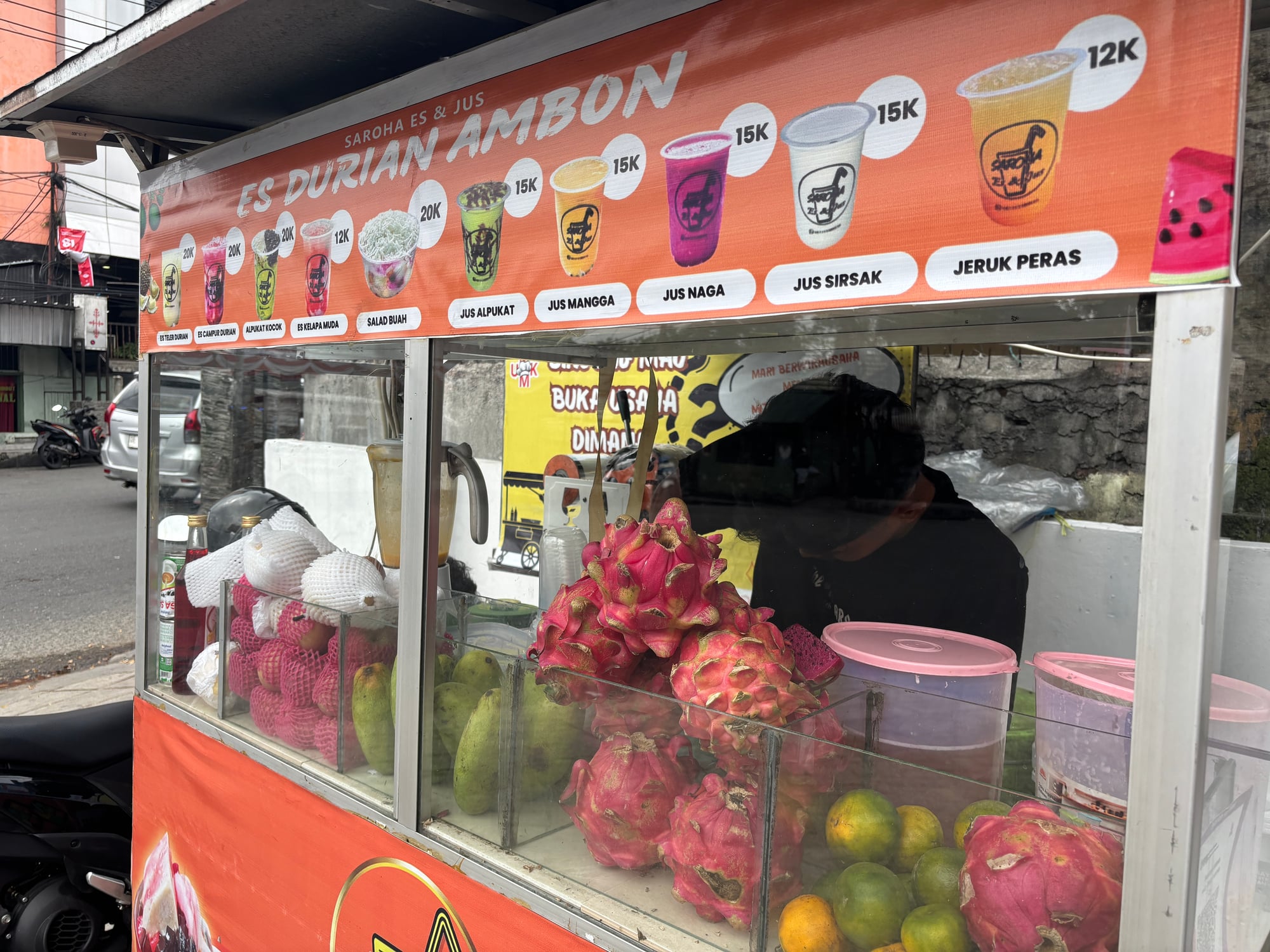 A street stand selling dragon fruit, mango, and fresh juices in Ambon