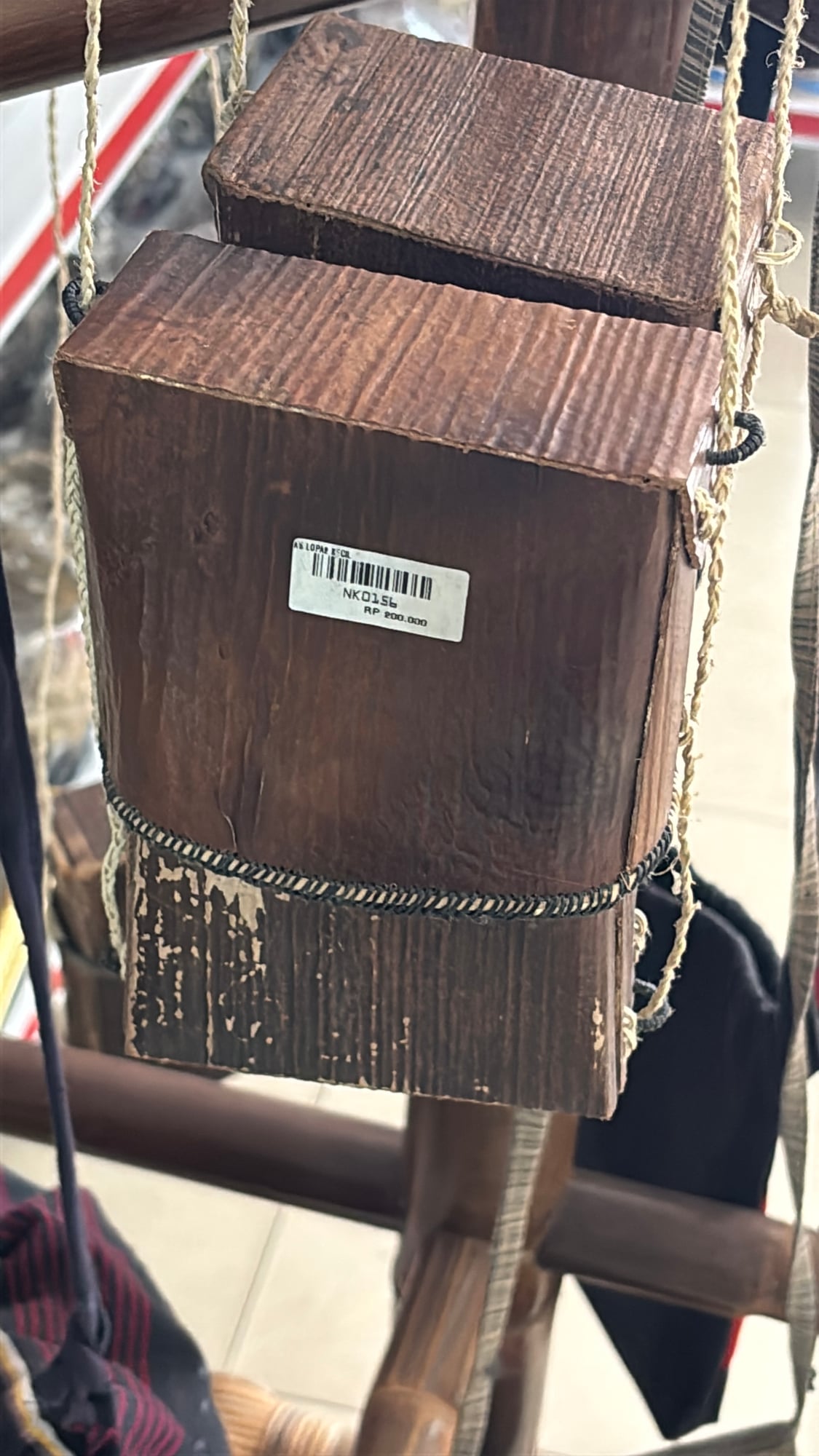 A traditional woven wooden bag hanging for sale at a market stall