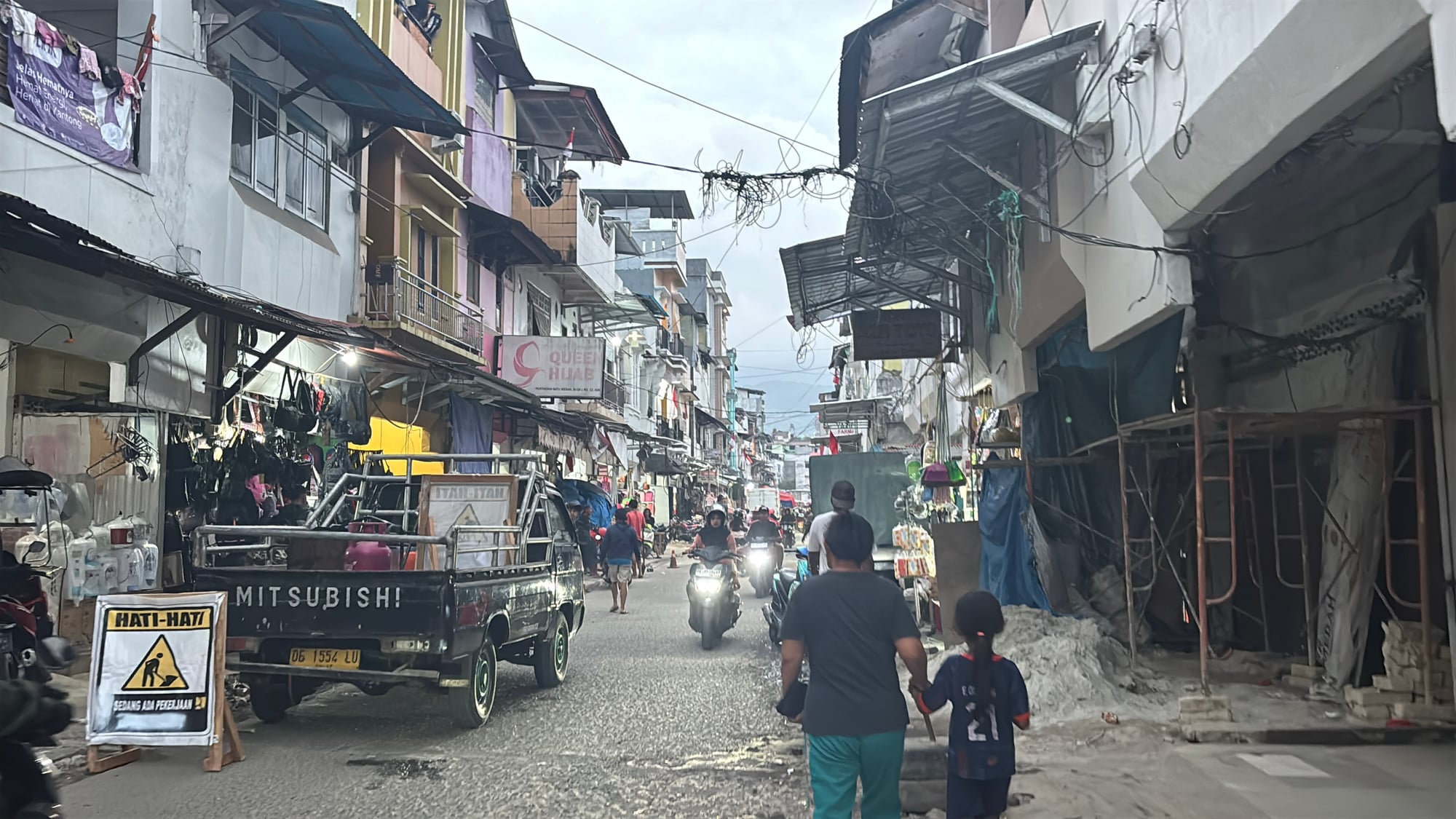 A narrow, busy street in Ambon's old town packed with shops and motorbikes