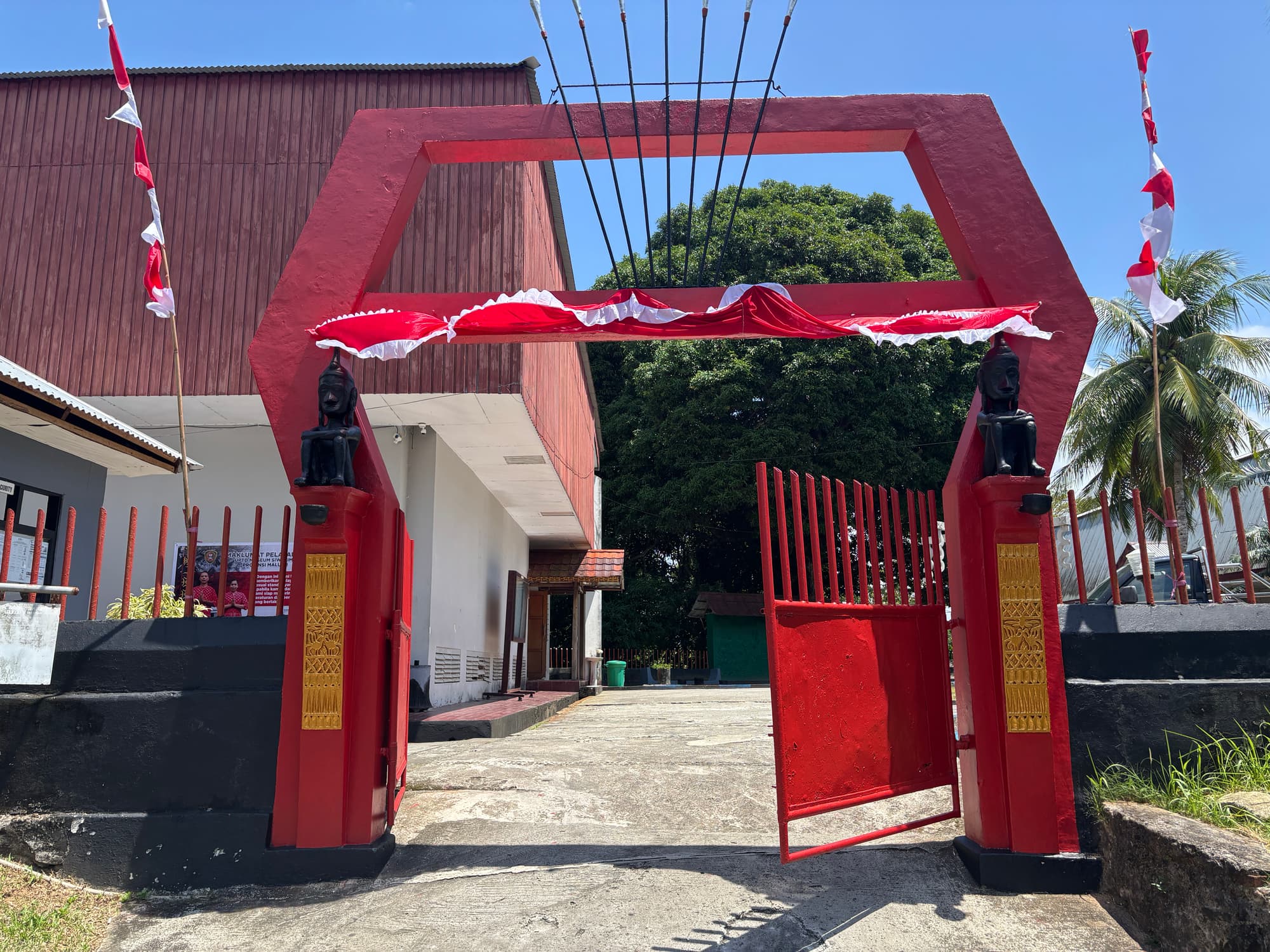 A red entrance gate decorated with Indonesian flags at a local museum