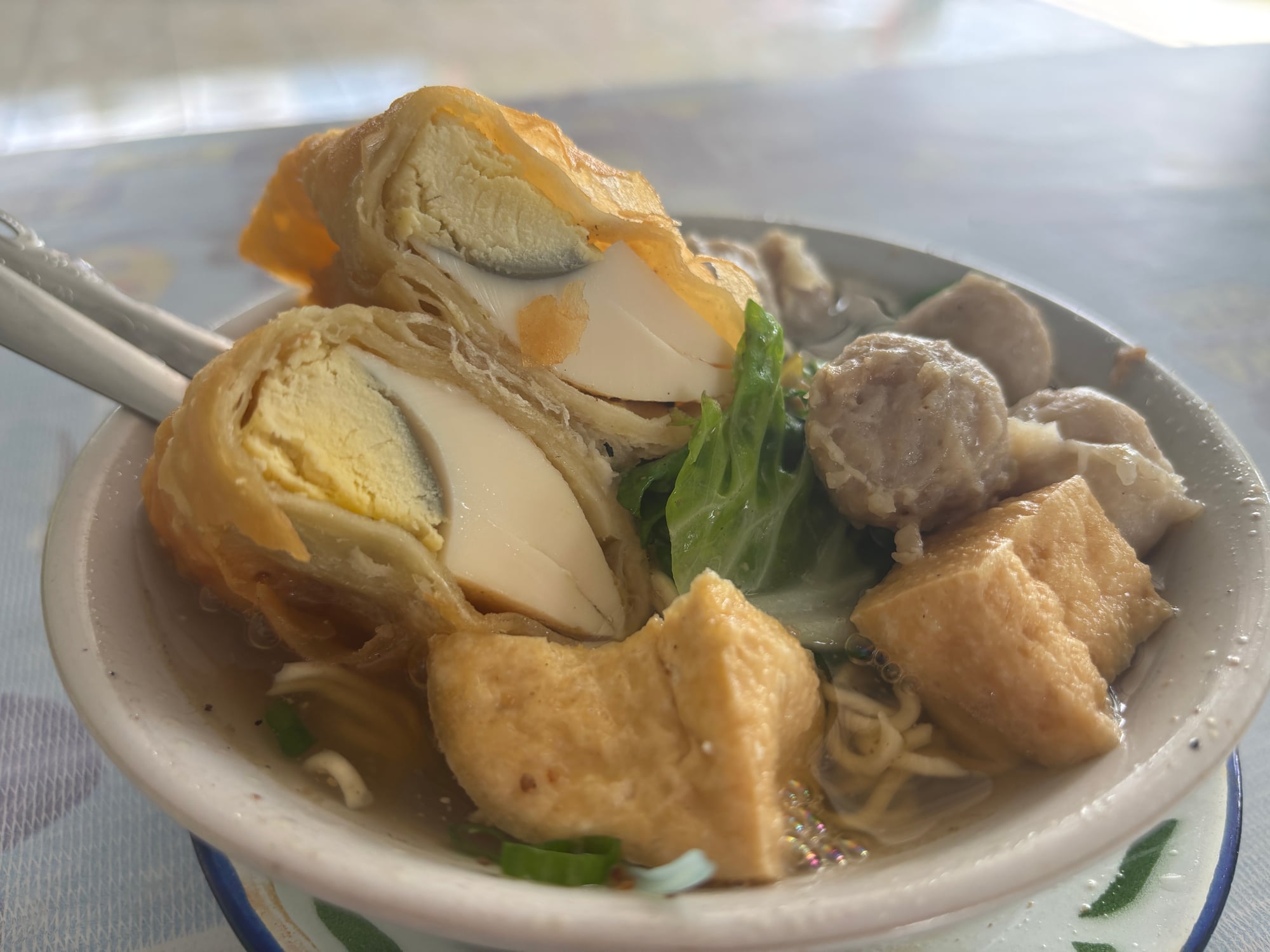 A bowl of Bakso Telur with meatballs, tofu, and egg wrapped in fried tofu skin