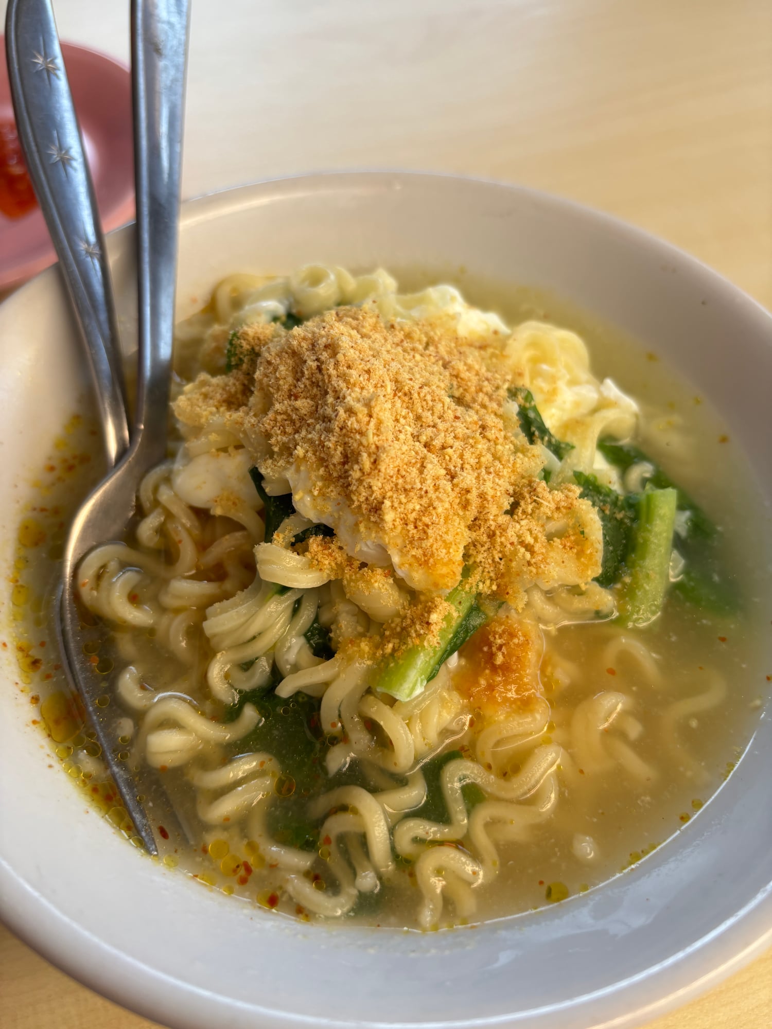A bowl of Sarumento, instant noodles topped with egg and fried shallots
