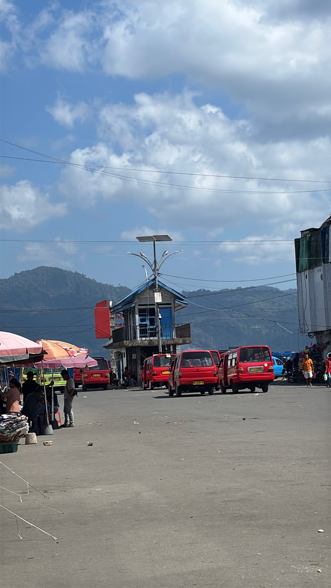 Red minibuses (angkot) lined up at the terminal near the port