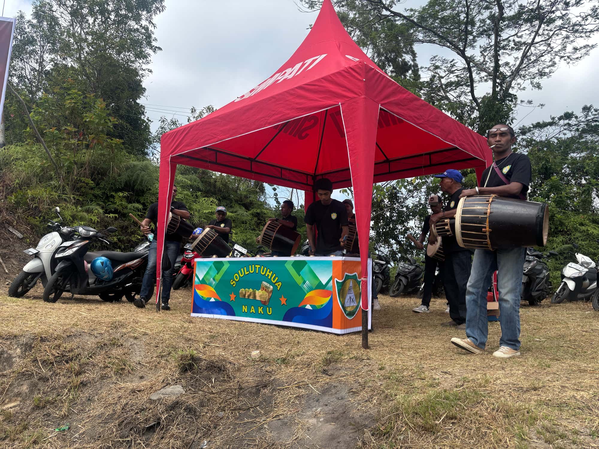 Musicians playing the Tifa, a traditional Maluku drum, under a red tent