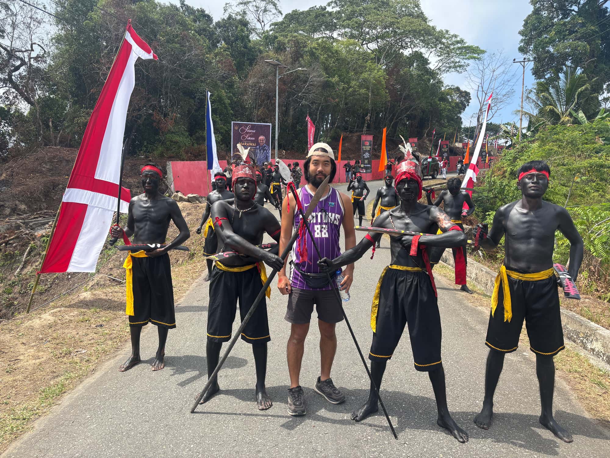 Posing with Cakalele war dancers in black body paint holding swords and spears