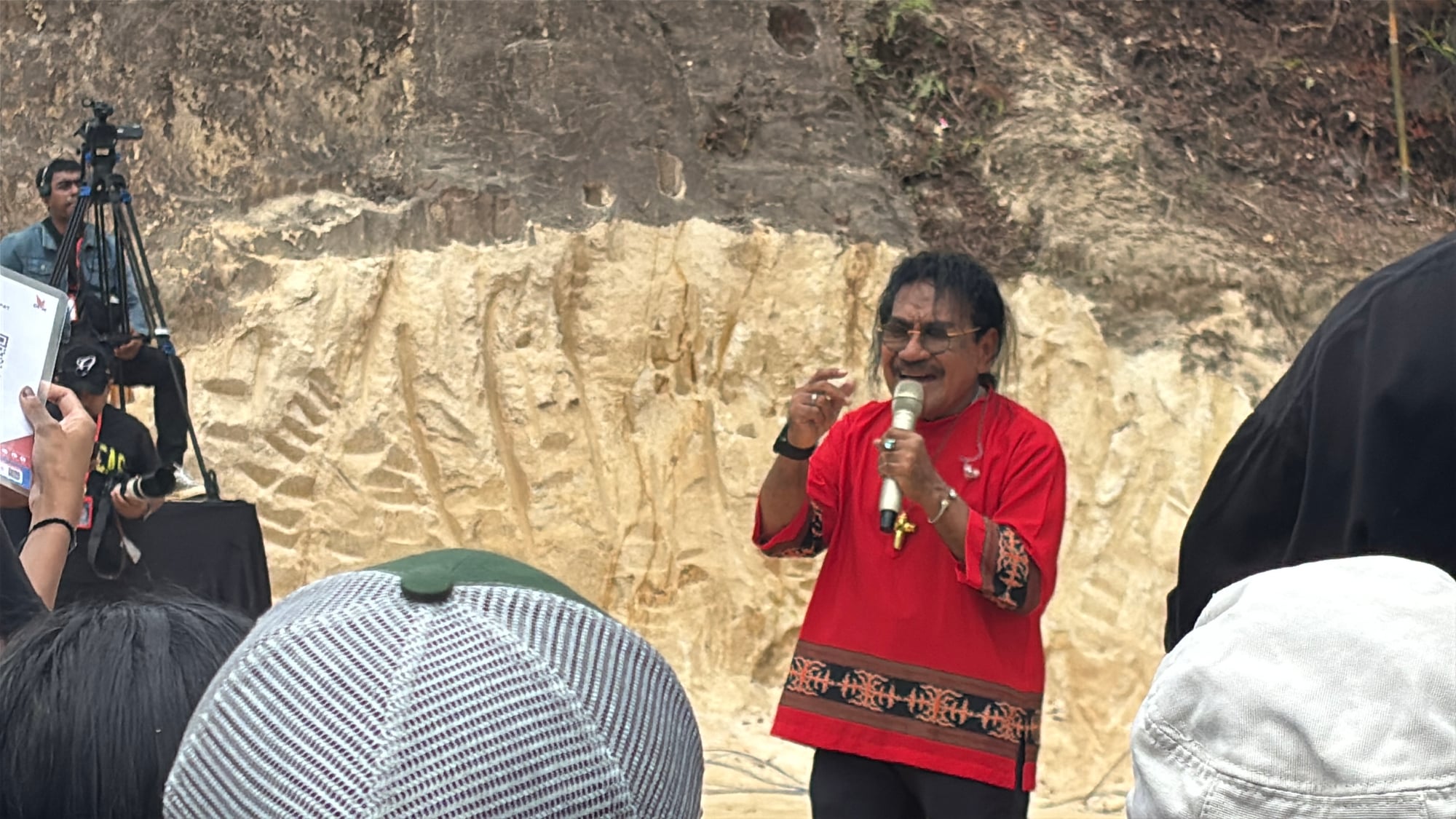 A performer singing into a microphone on stage after the Tari Lenso
