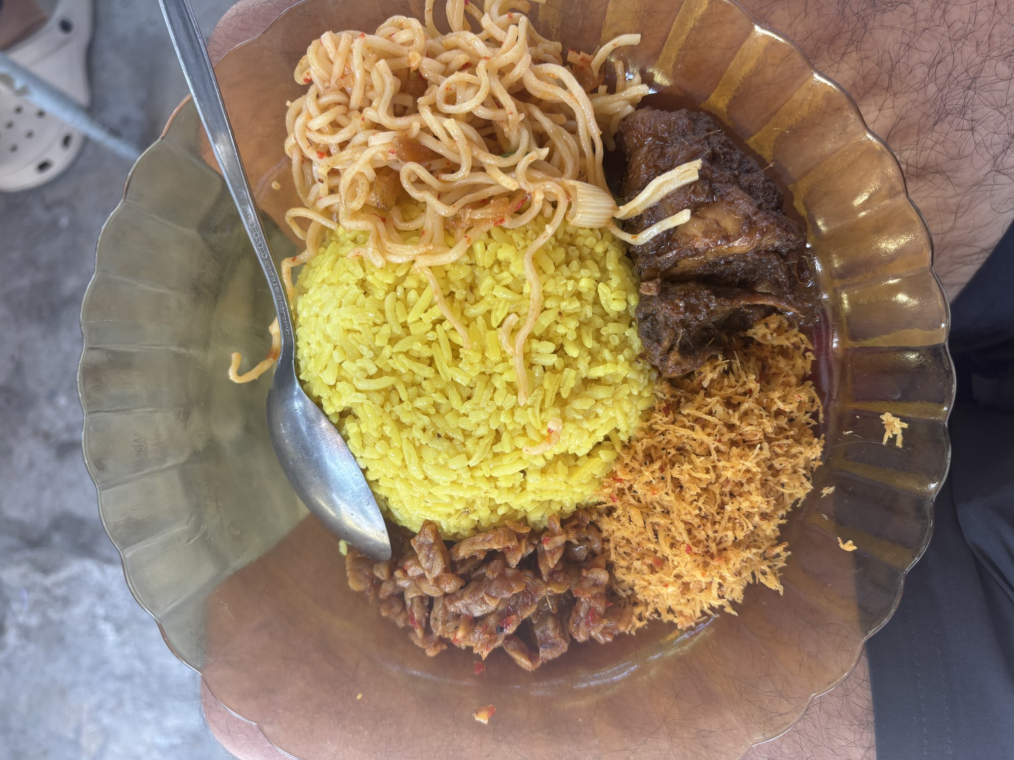 A plate of Nasi Kuning, turmeric rice topped with meat and spaghetti, from a Palu street stall