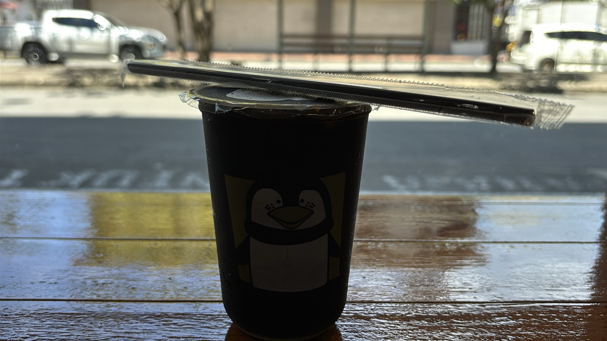 An iced coffee from a local cafe, sitting on a rainy street-side table