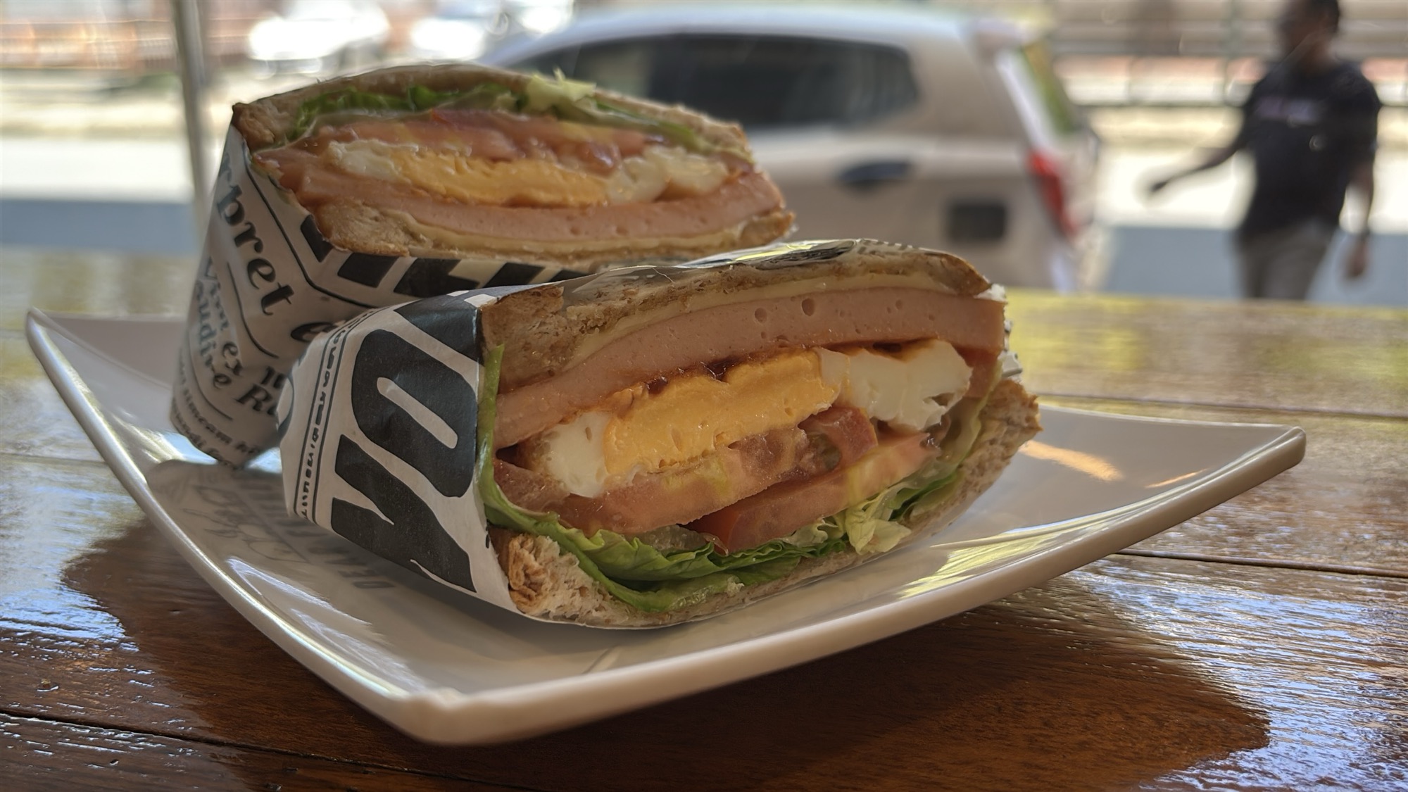 A wrapped sandwich sliced in half, packed with egg, ham, and vegetables