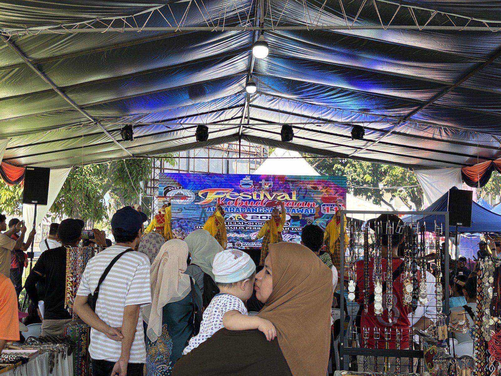 A crowd gathered under a festival tent watching a traditional performance on stage