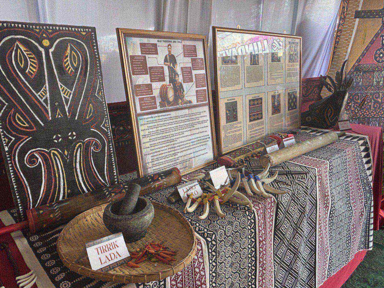 A Toraja booth display with traditional textiles, carvings, and informational posters