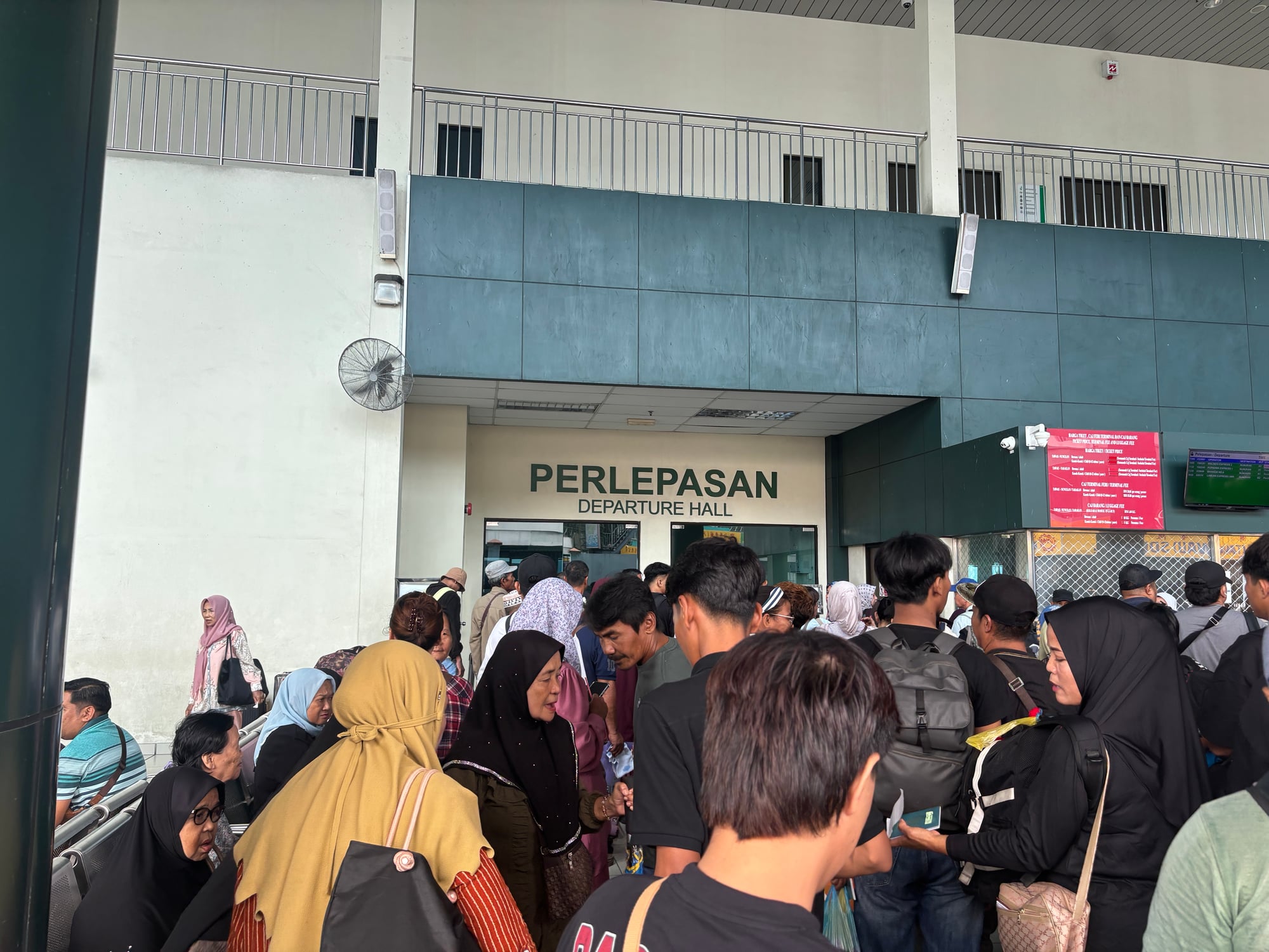 A crowd of passengers waiting in the Tawau ferry departure hall