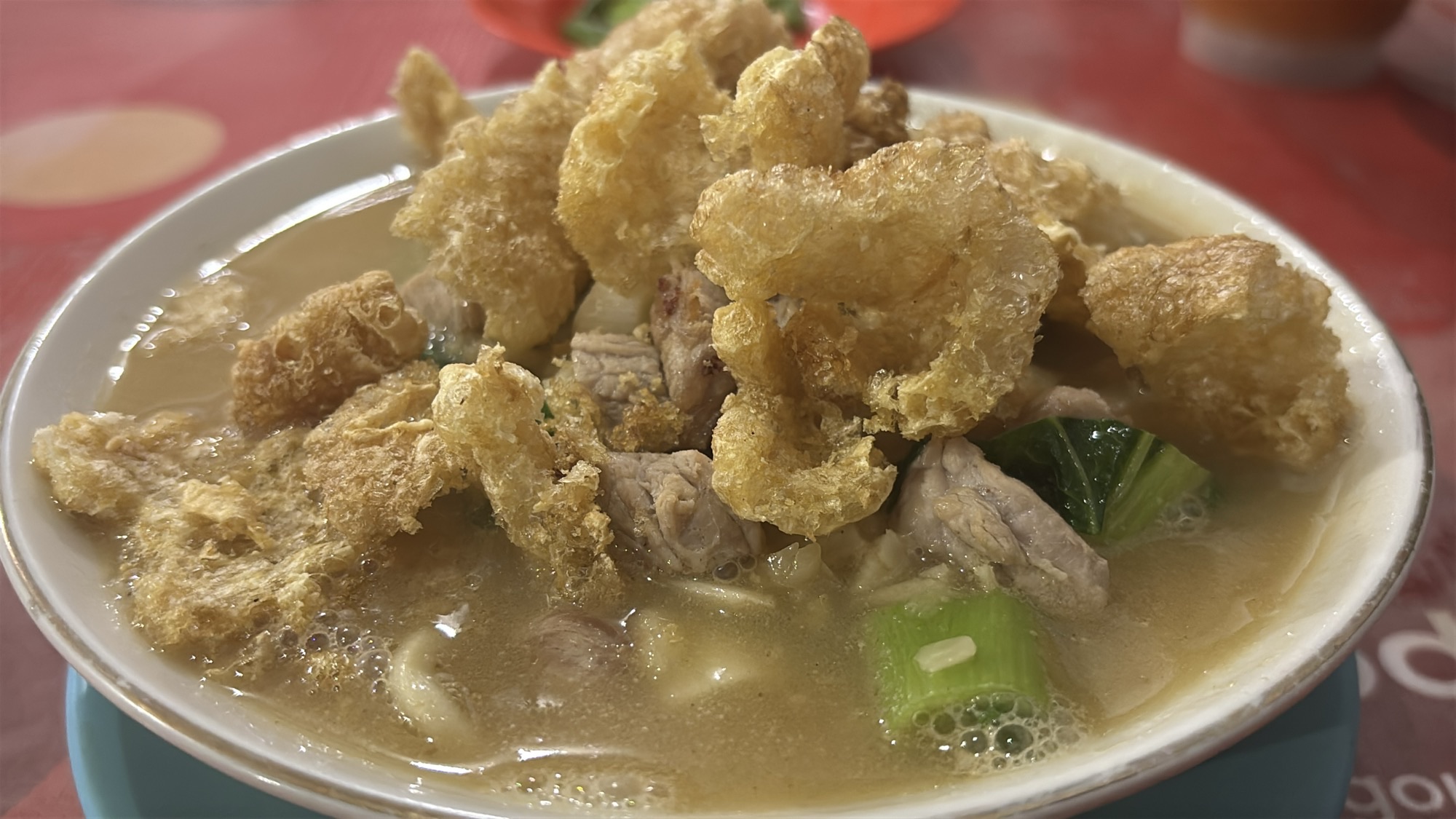 A bowl of soup with pork and crispy fried pork skin for dinner