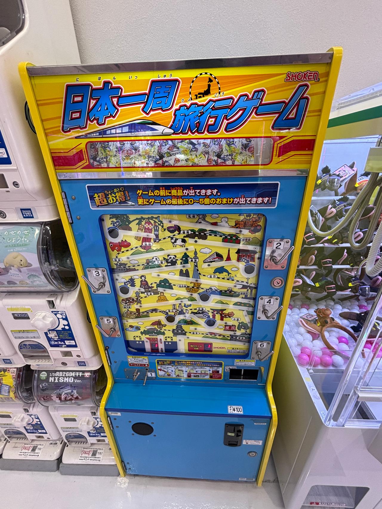 A colourful Japanese vending machine featuring a travel-themed game, displaying various icons and characters related to travel.