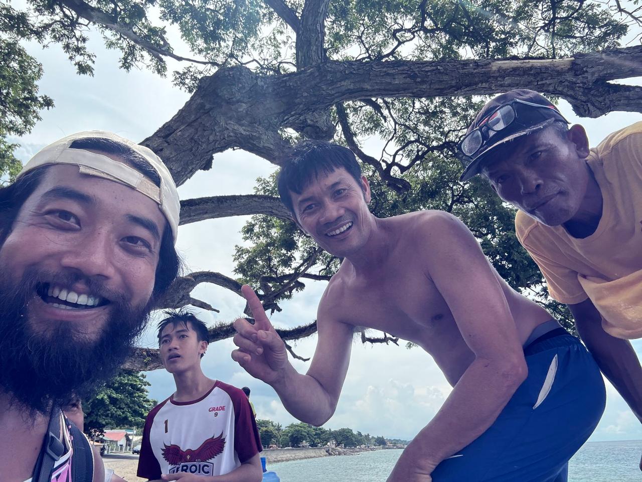 Posing with a group of locals under a tree by the water at a second Father's Day gathering