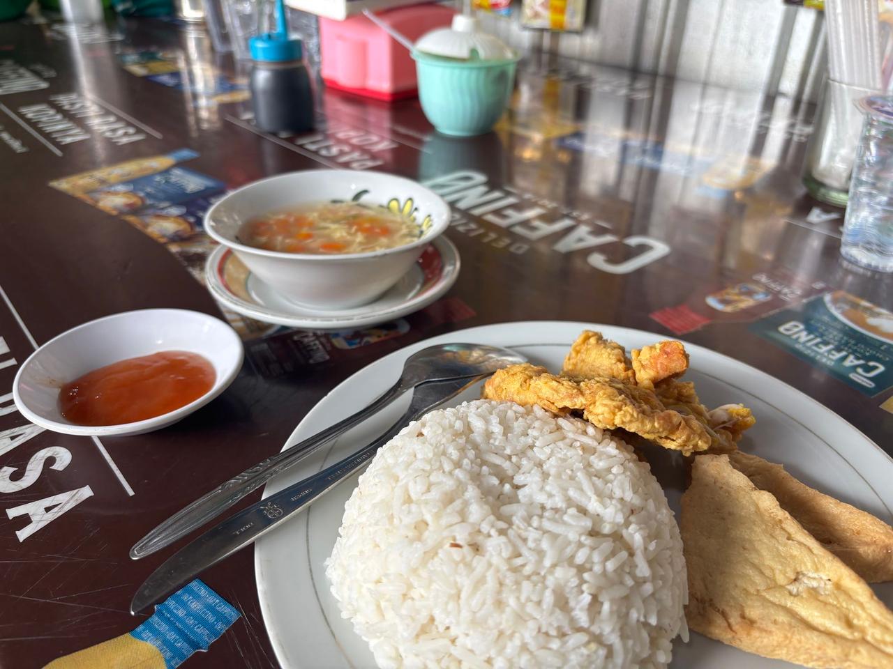 Sepiring nasi dengan ayam goreng, semangkuk sup, dan sambal di sebuah kafe