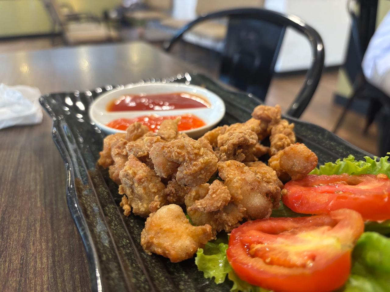 A plate of fried chicken karaage with lettuce, tomato, and ketchup at a cafe