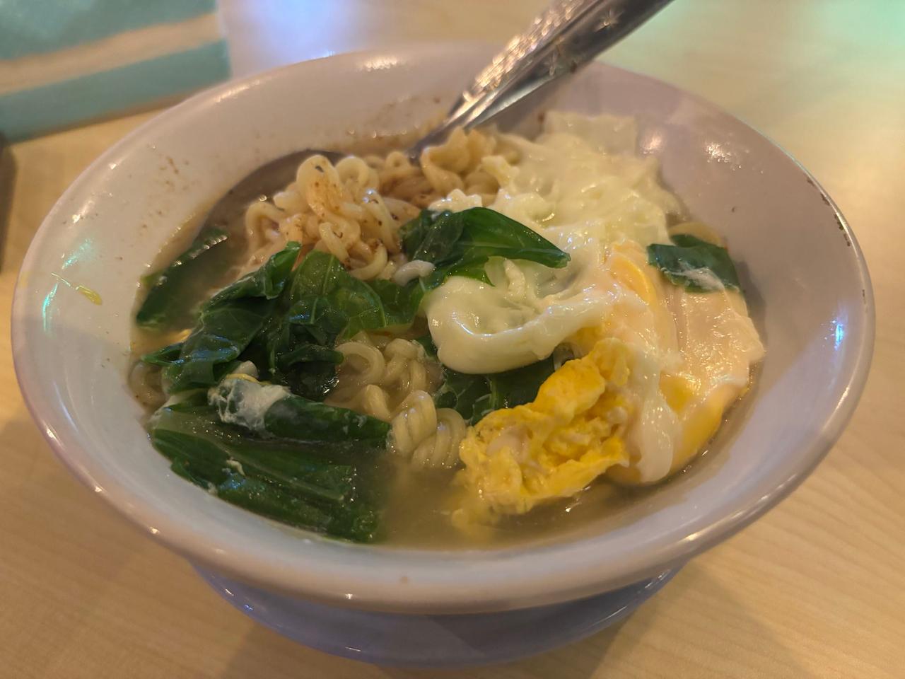 A bowl of instant noodle soup with egg and vegetables for dinner in Ambon