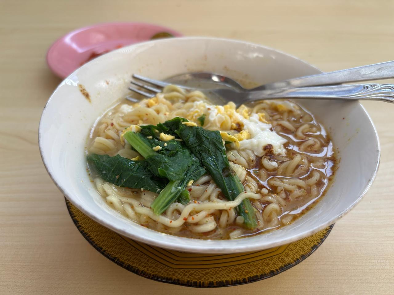 A bowl of Sarumento egg noodles with vegetables at a street stall