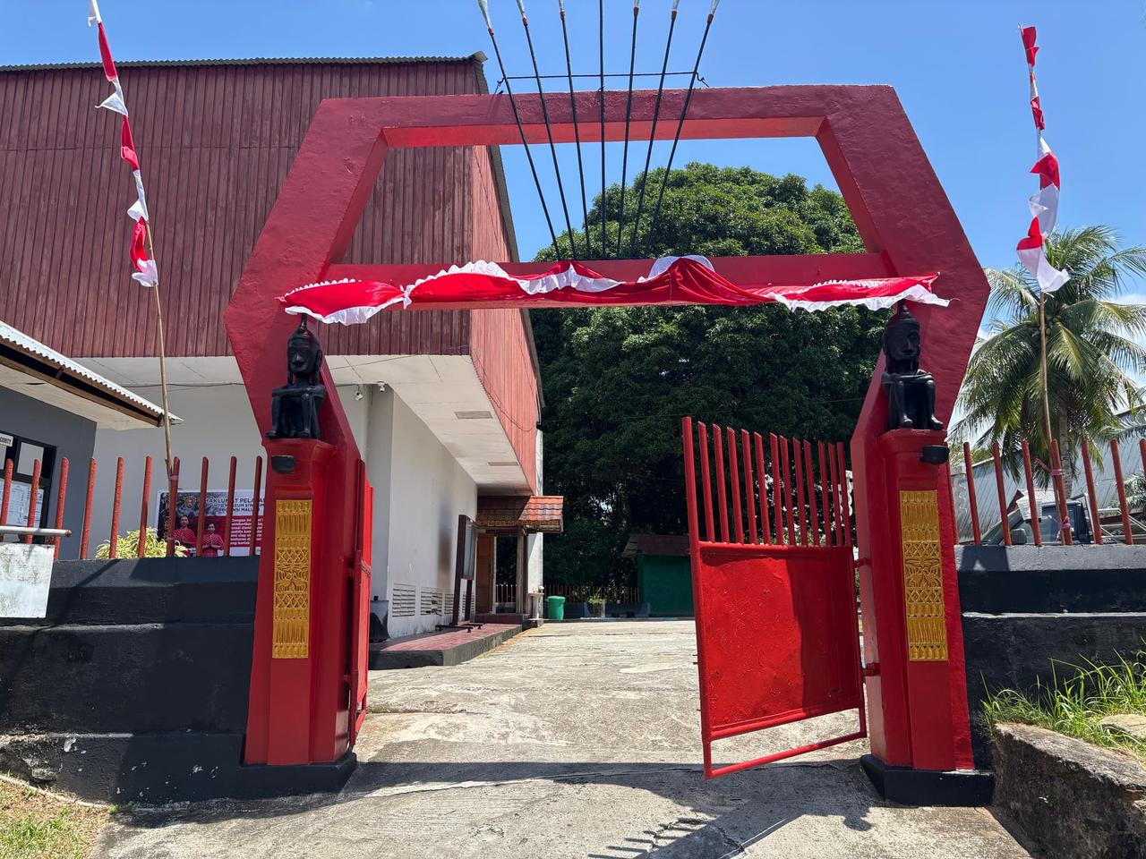 A red entrance gate decorated with Indonesian flags at a local museum