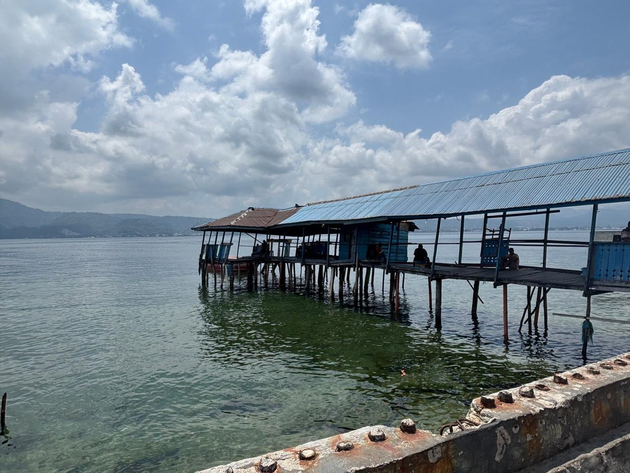 An old, weathered wooden jetty extending out over the water