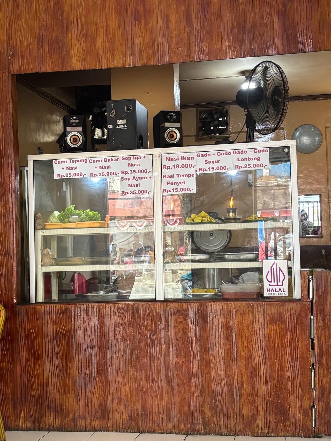 A handwritten menu board listing Cumi Bakar, Sop Iga, and other dishes with prices