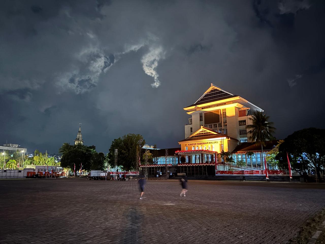 The Kantor Gubernur Maluku building lit up at night with a stage being set up nearby