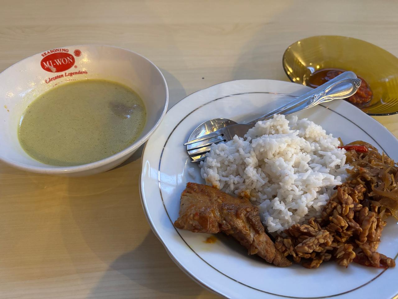 A plate of Nasi Ikan with rice, fish, tempe, and a side soup at a local warung