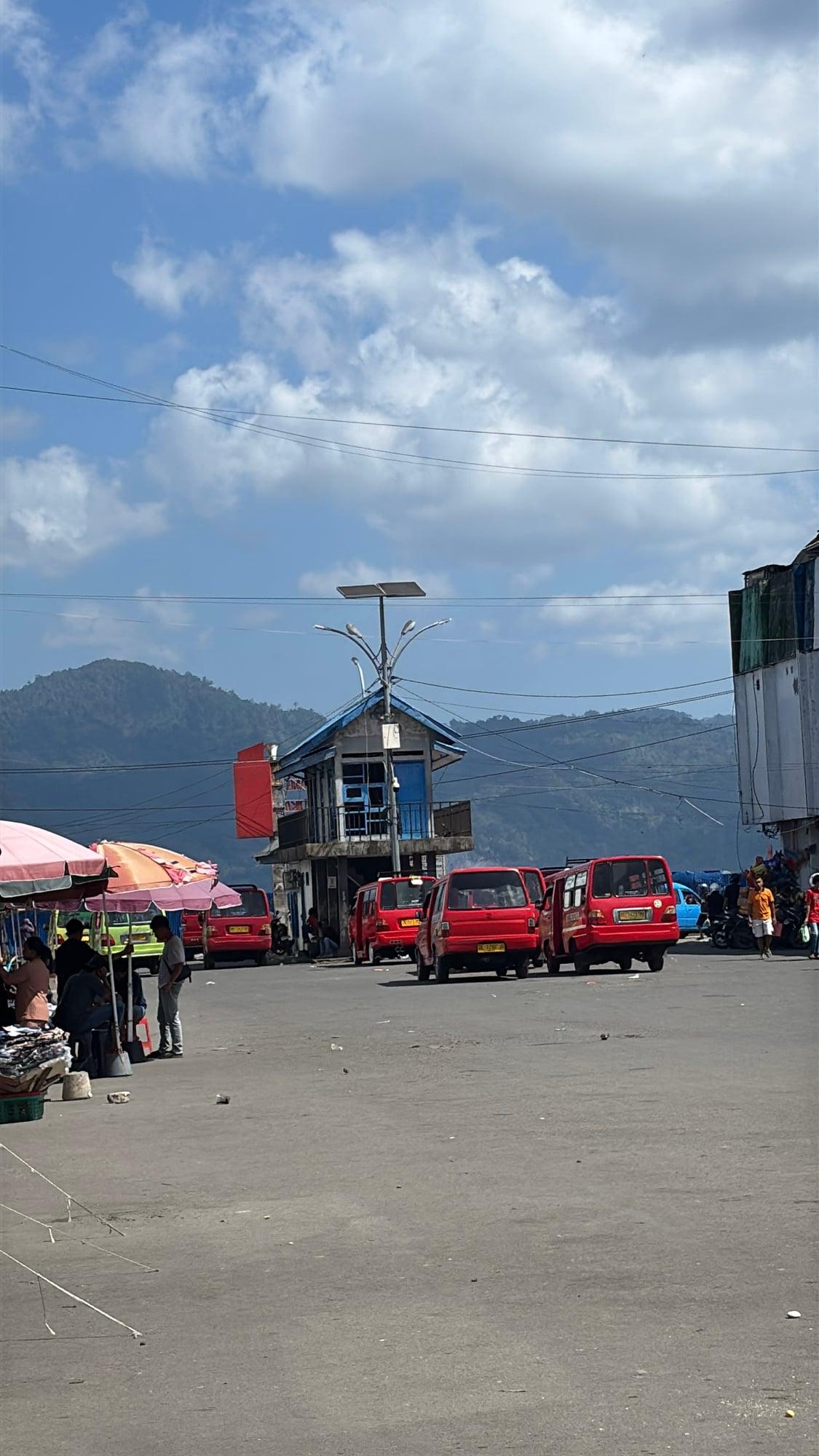 Red minibuses (angkot) lined up at the terminal near the port