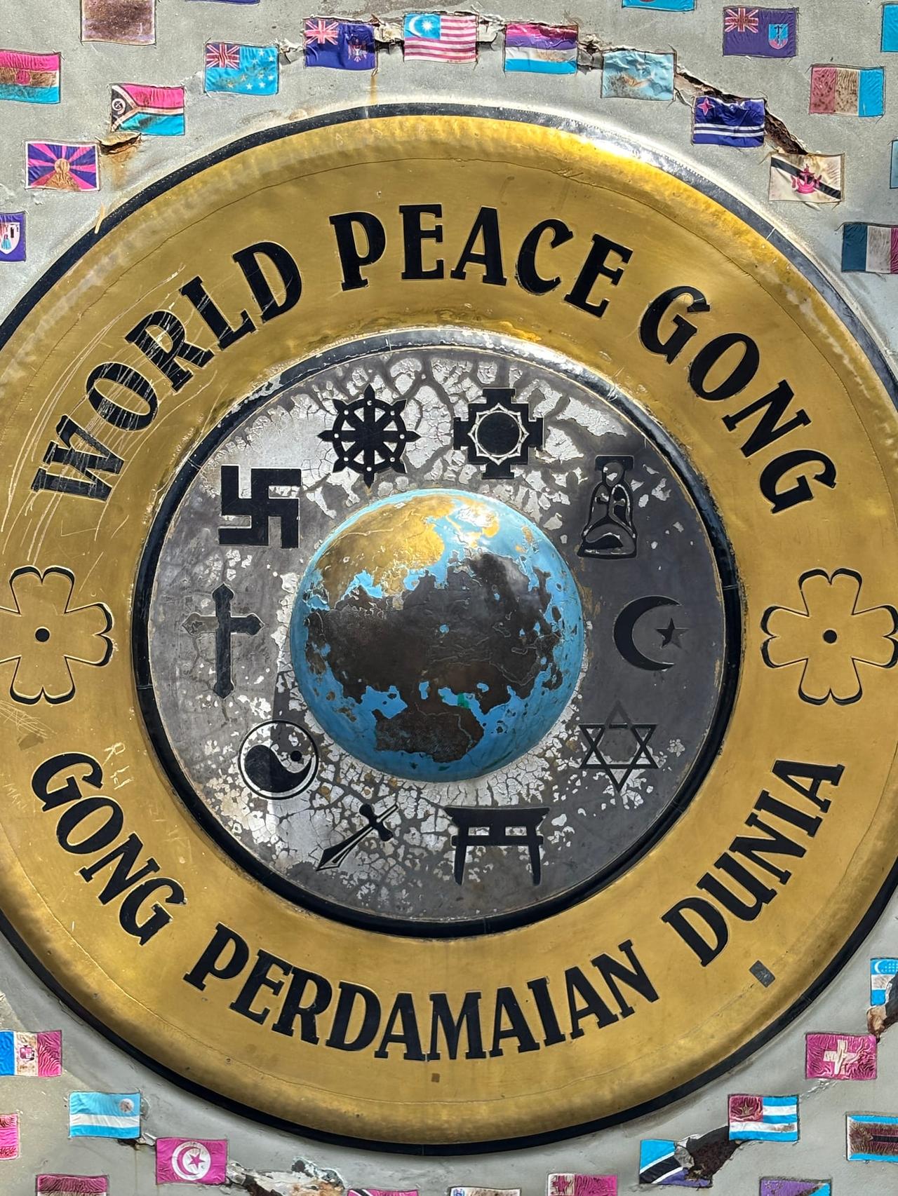 A close-up of the World Peace Gong plate showing world flags and religious symbols around a globe