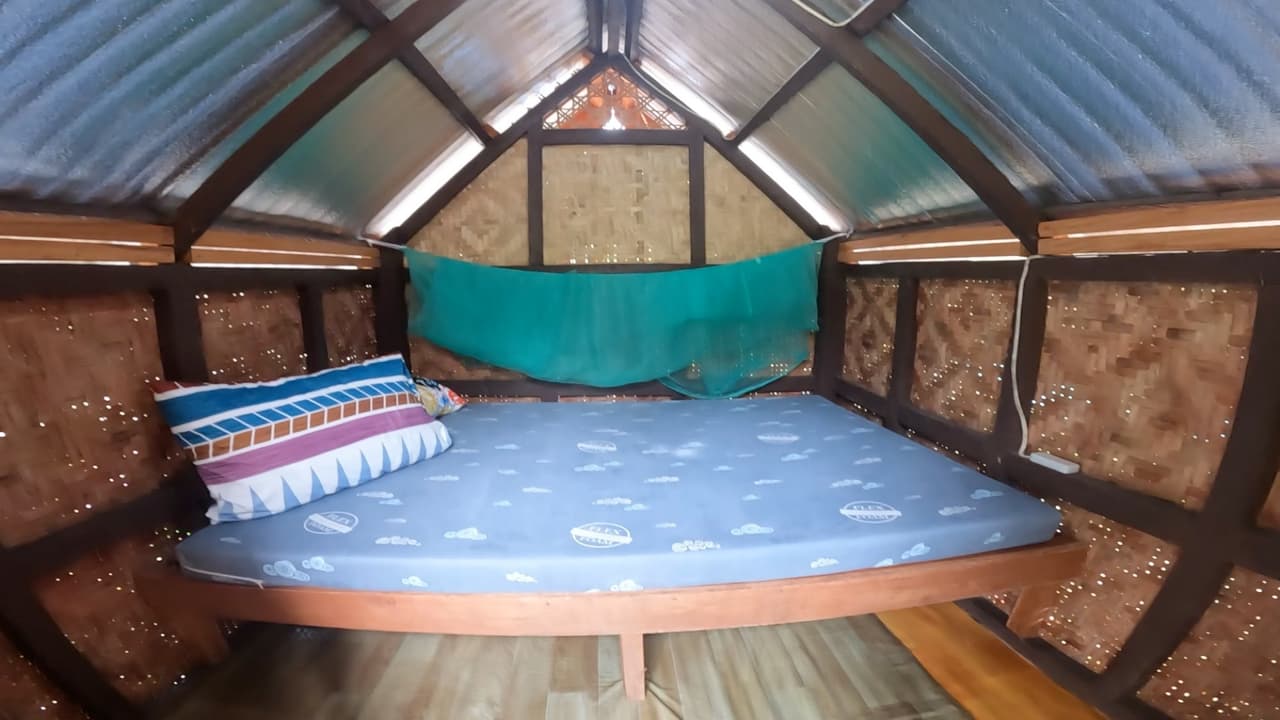 Interior of a bahay kubo in Bohol with woven bamboo walls, bed and mosquito net