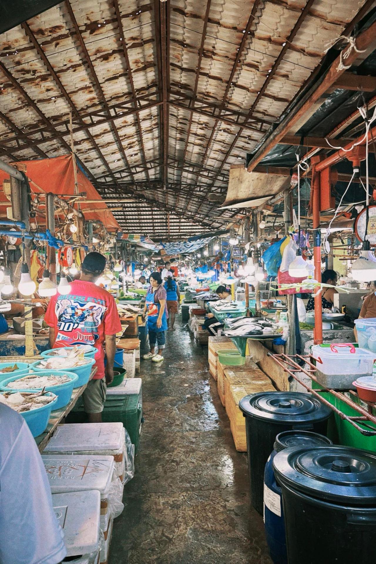 Inside a bustling local market in Bais City with vendors and fresh produce