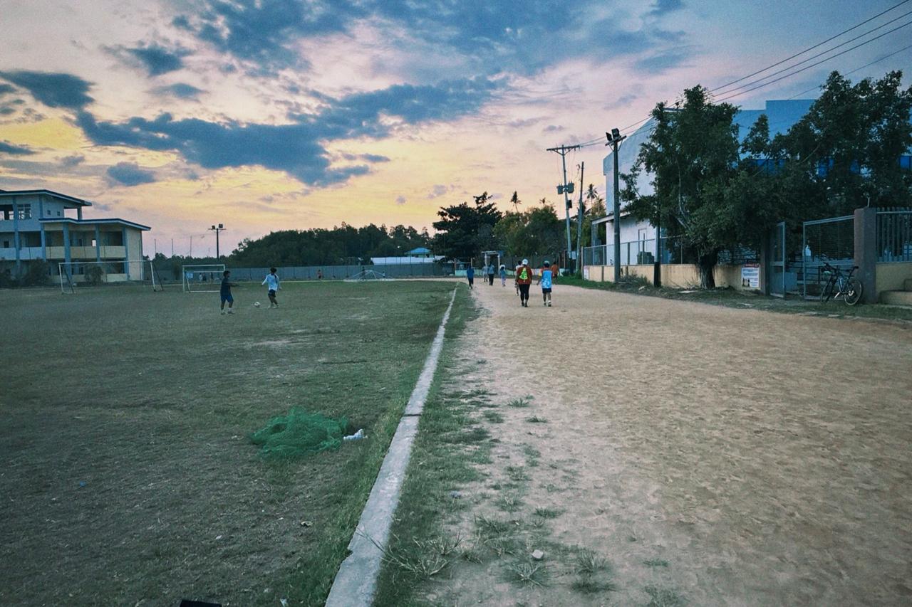 Locals playing football and walking laps at the Balamban sports ground at dusk