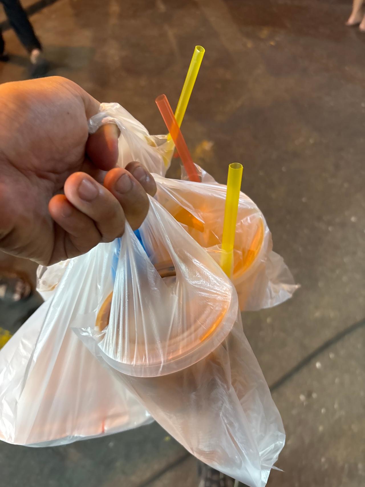 A bag of drinks with colorful straws, ready to go