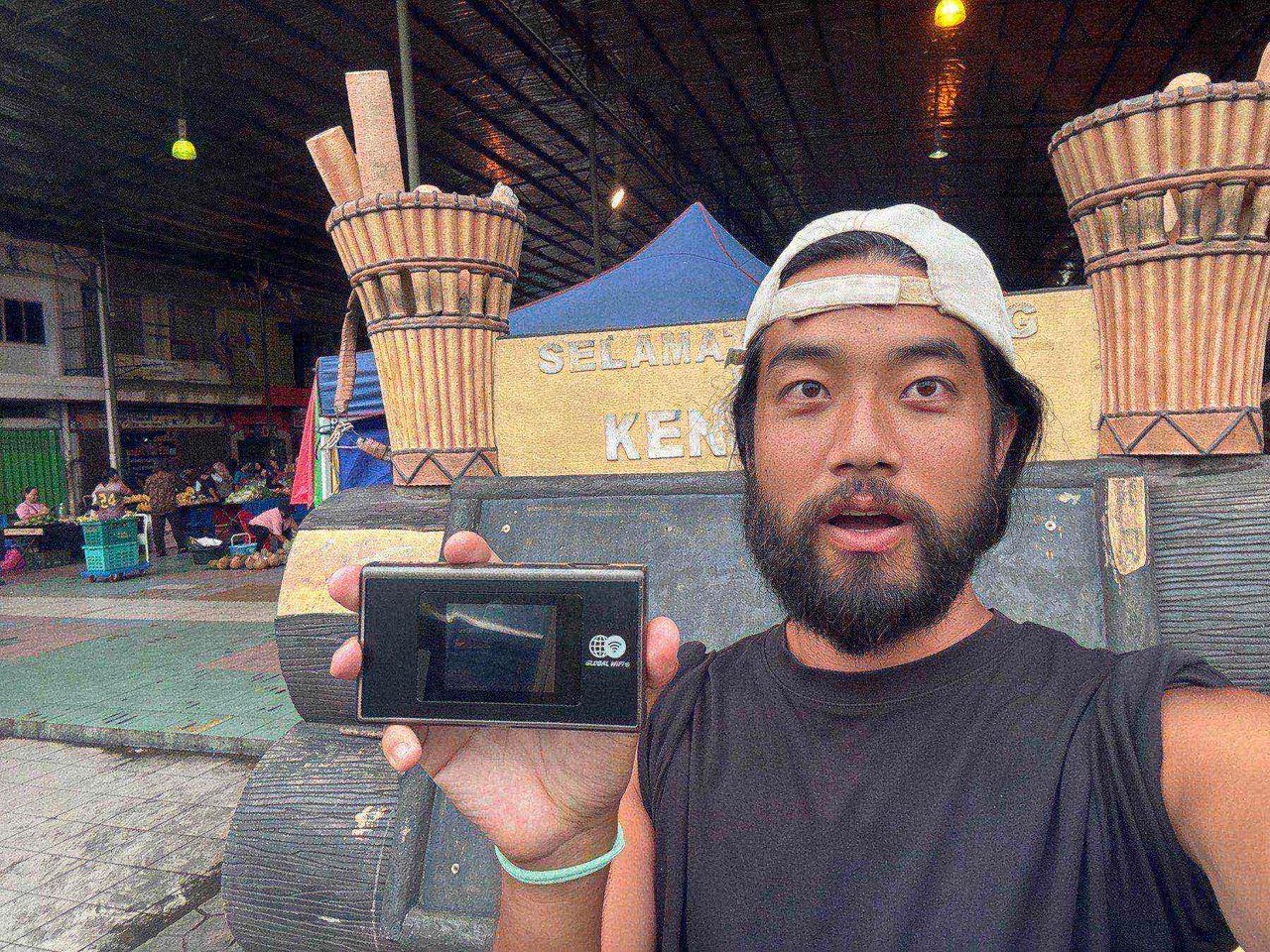 Holding up my Global WiFi device in front of the Keningau market entrance