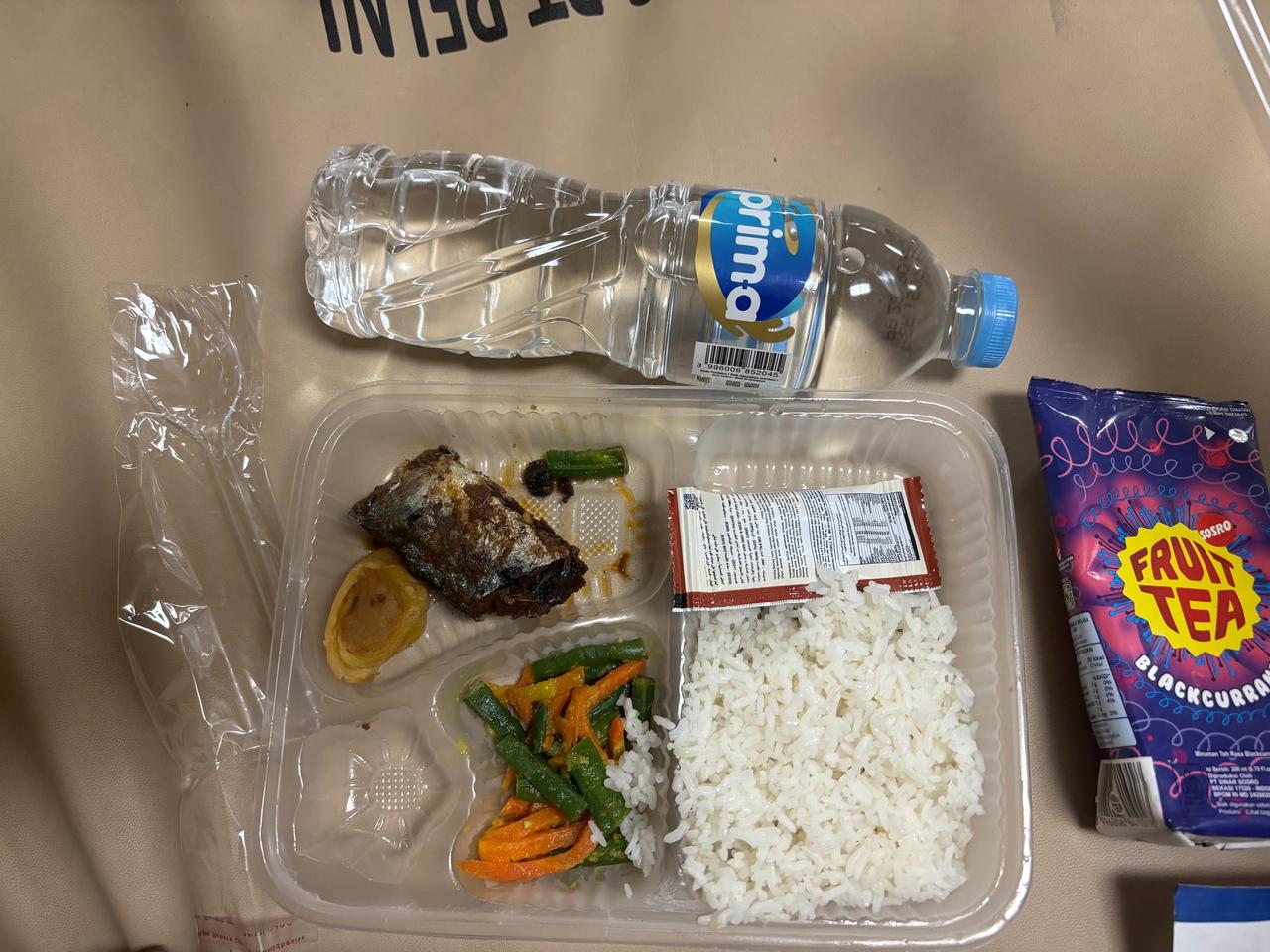 Nampan makan malam berisi nasi, sayur, ikan, dan sebotol air di feri PELNI