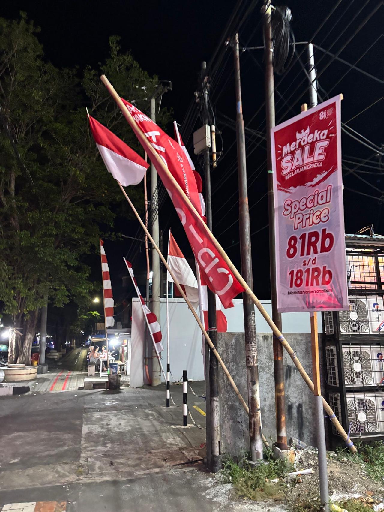Bendera Indonesia dan spanduk "Merdeka Sale" menghiasi jalanan Bitung di malam hari