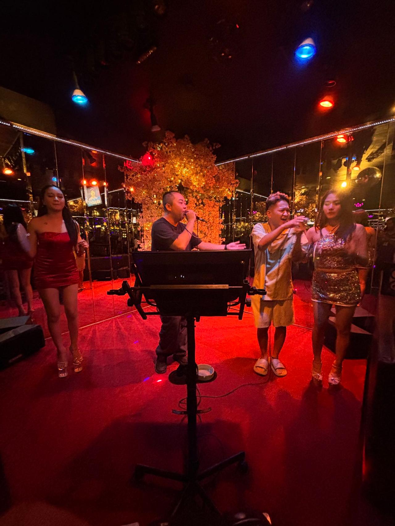 Singing karaoke with friends under red and blue lights at a local KTV club