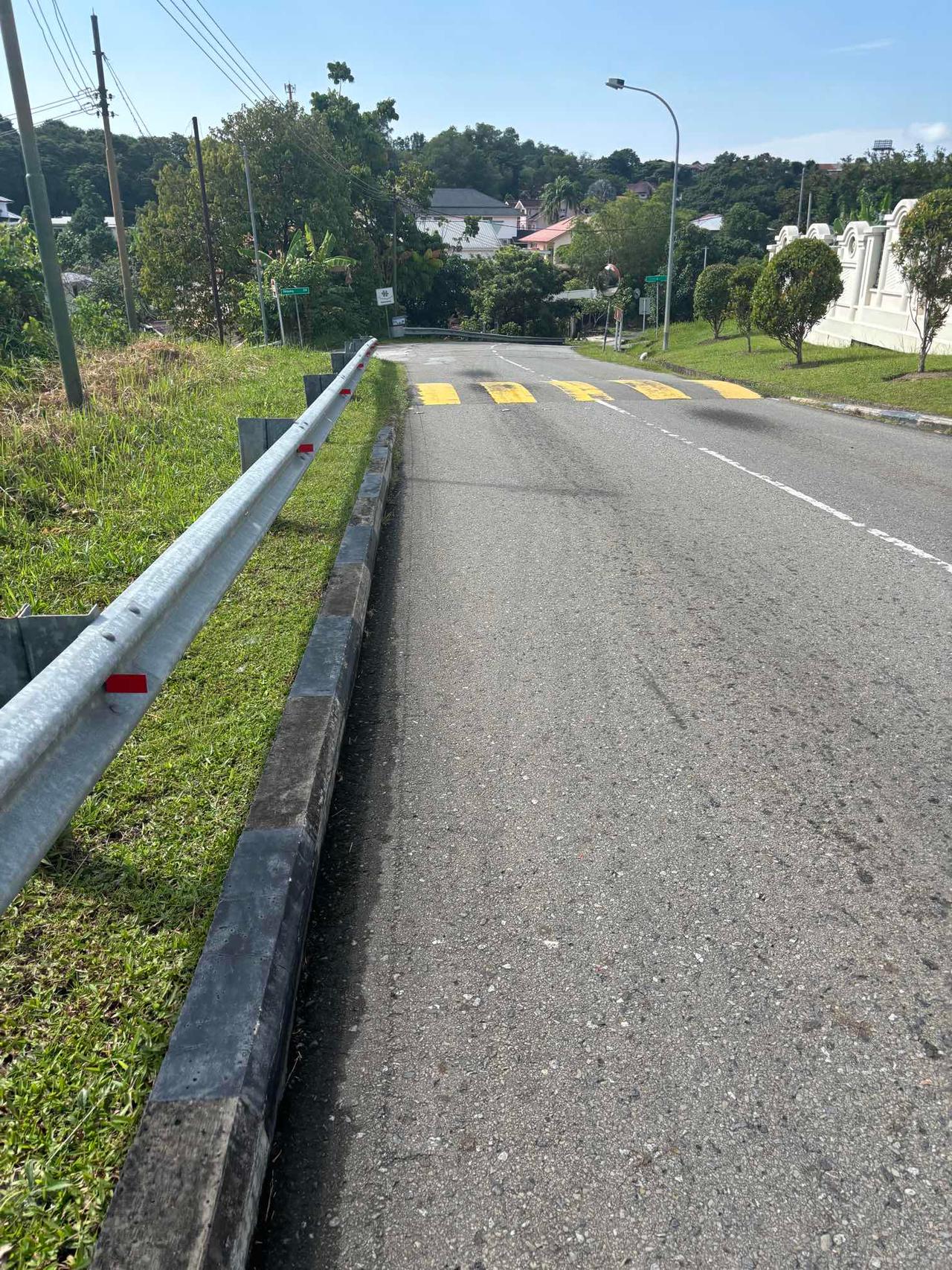 A paved road with a guardrail and no walking shoulder on the outskirts of Bandar Seri Begawan