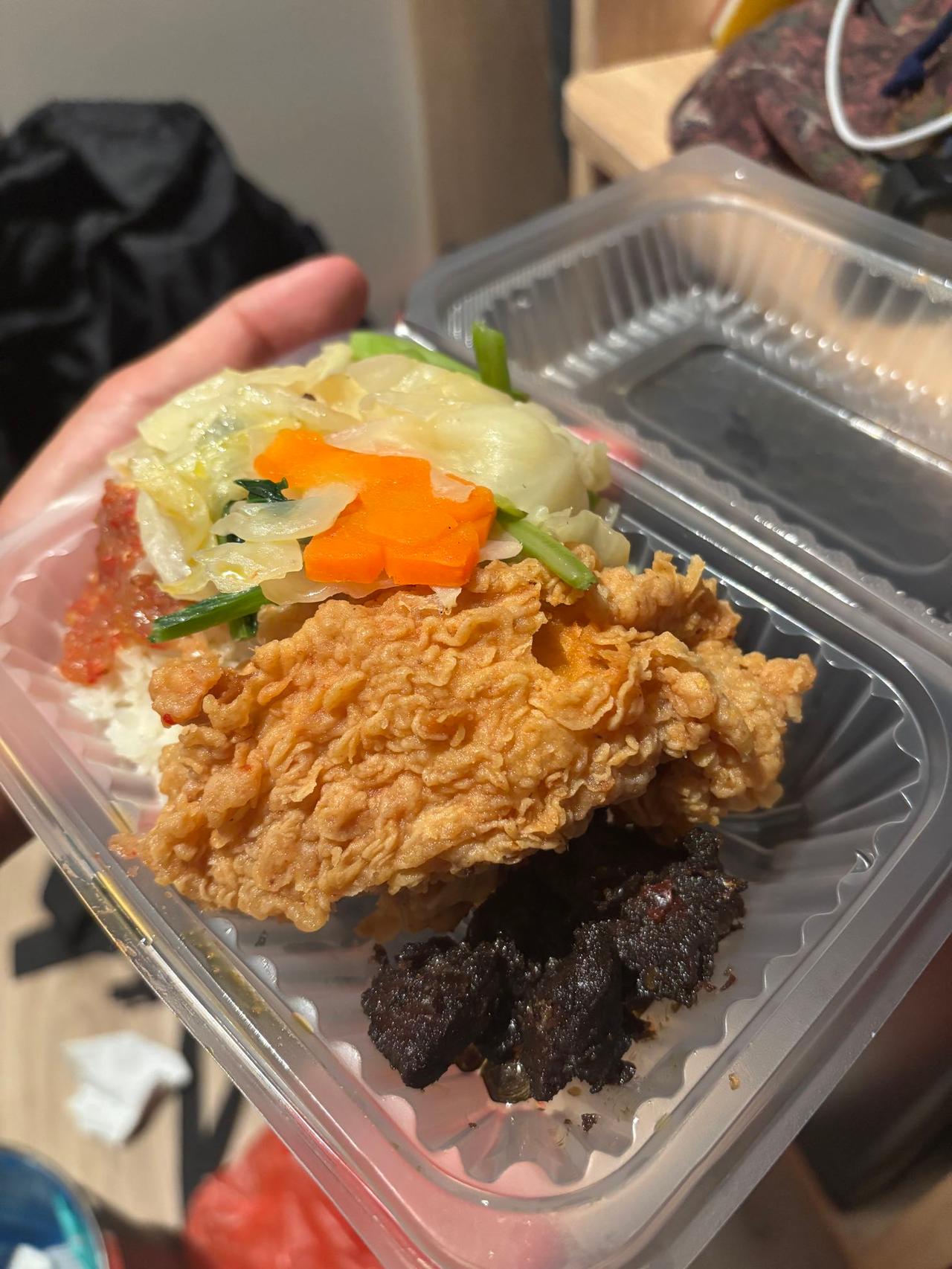 A takeout plate of rice, fried chicken, vegetables, and beef at a local diner