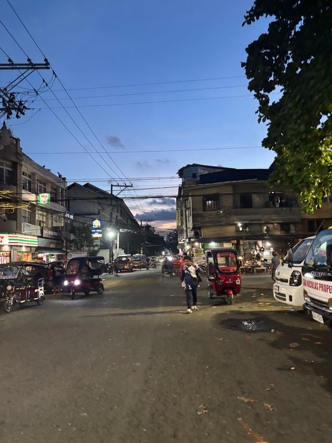 A busy Cebu City street at dusk filled with tricycles and traffic