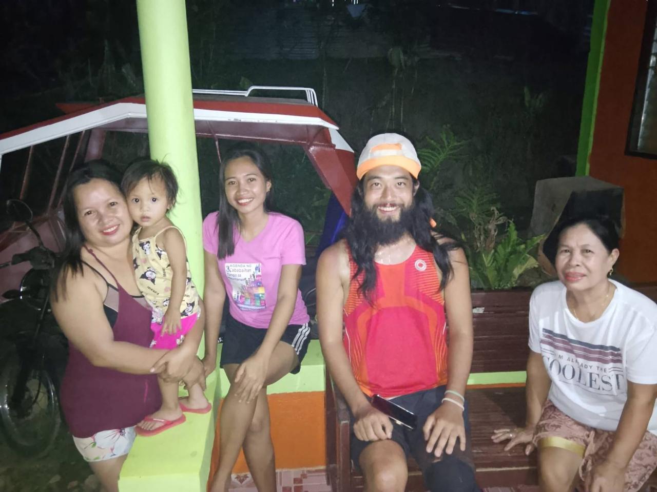 Posing at night with the local family who welcomed him into their home