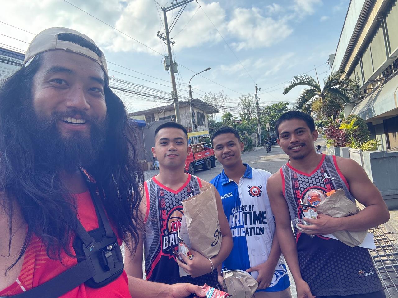 Three friendly local guys holding snacks and standing together on a Bohol street