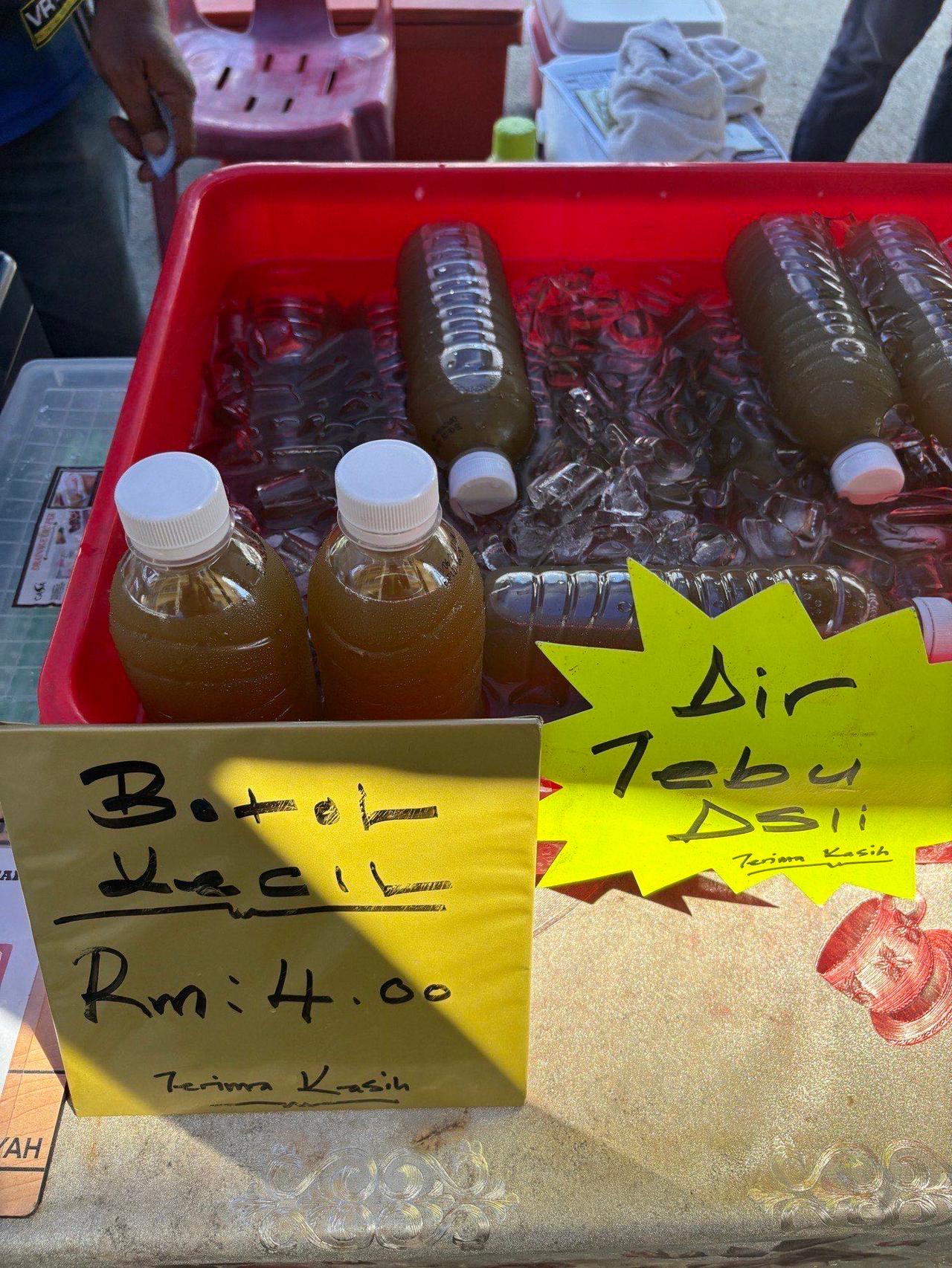 Bottles of the local Air Tebu drink chilling on ice at a market stall