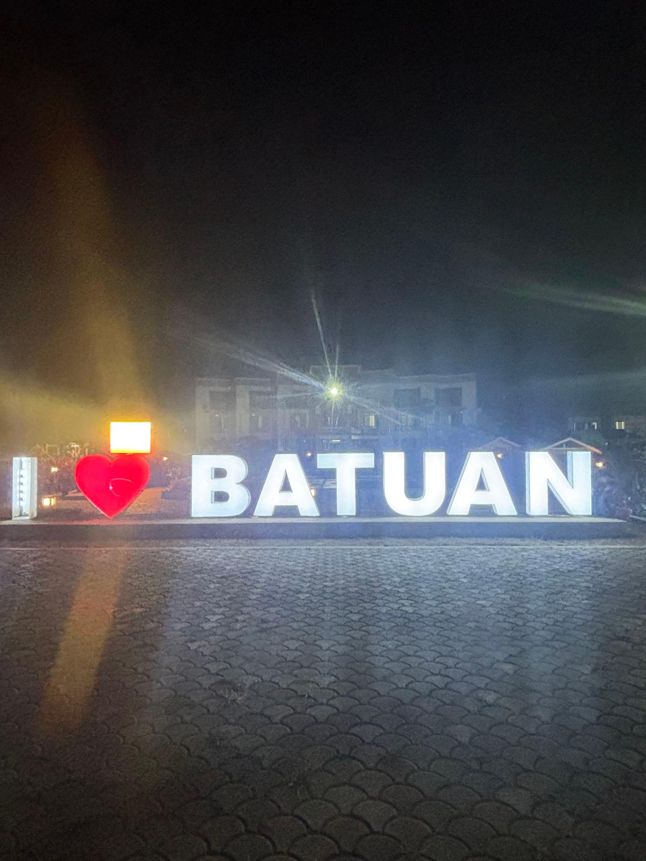 A lit-up "I Love Batuan" sign glowing at night in the town square