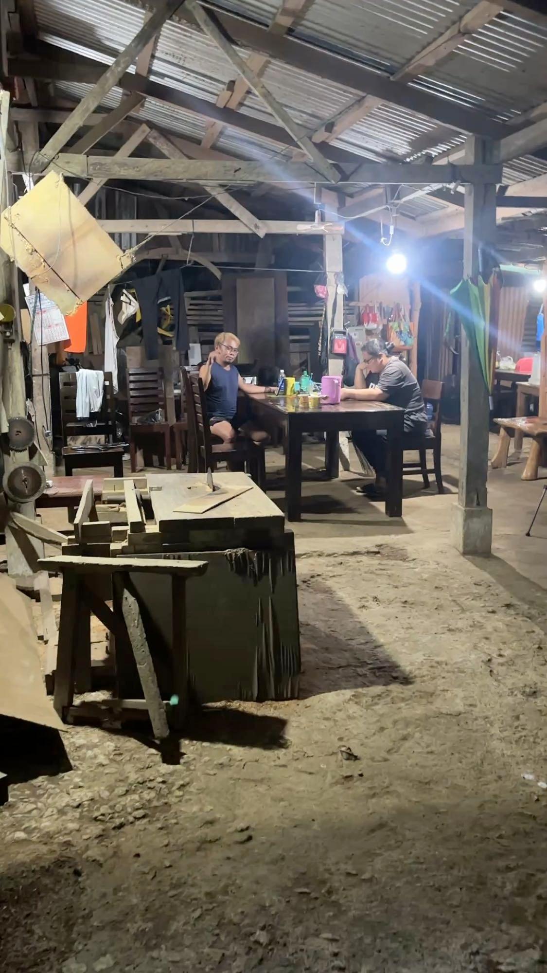 Sitting and talking with a local family at a table inside their home workshop at night