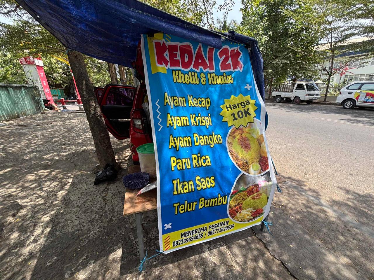 Sebuah spanduk pinggir jalan Kedai 2K yang mengiklankan hidangan ayam dan ikan mulai dari Harga 10K