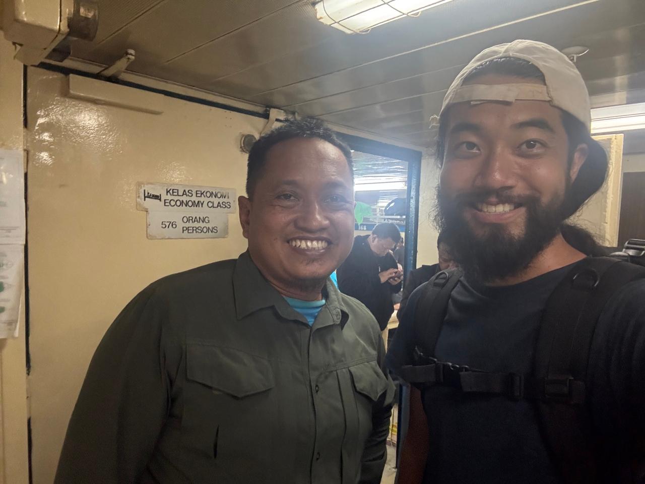 Penulis berdiri bersama Murdianto, sesama penumpang, di samping papan tanda Economy Class di dalam feri