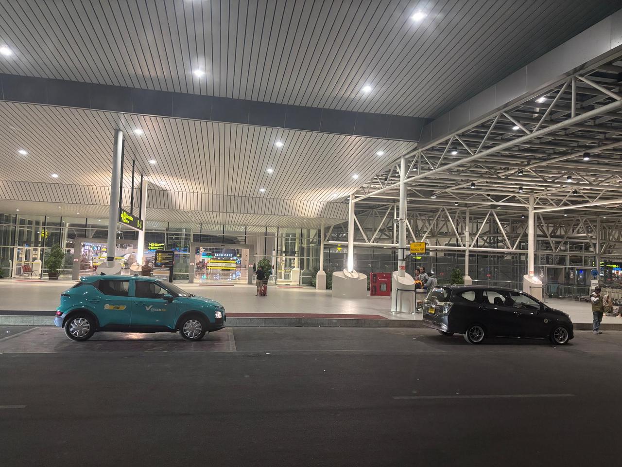 A quiet airport terminal at night with taxis waiting under bright lights